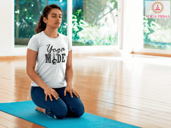 Junge Frau beim Yoga kniet auf Matte Leggins Yoga MADE Shirt weiß